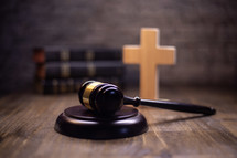 A gavel with a bible and illuminated cross in the background