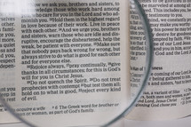 magnifying glass over pages of a Bible 