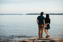 a couple standing on a rocky shore 