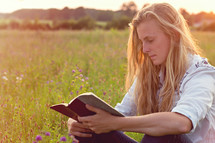 woman reading a Bible in a field of wildflowers 
