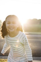 a smiling toddler girl in pigtails laughing in the sun.