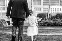 a father walking holding hands with his daughter 