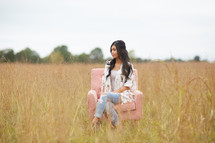 a young woman sitting in a chair in a field