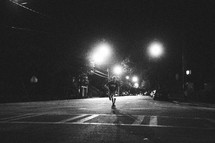 man skateboarding in the middle of the road at night 