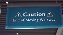 Close up of a "Caution End of Moving Walkway" sign at an airport.