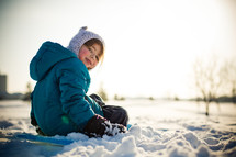 child sitting on a sled in the snow