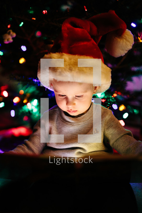 a child reading a book under a Christmas tree 