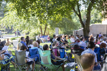 people sitting in chairs at an outdoor concert