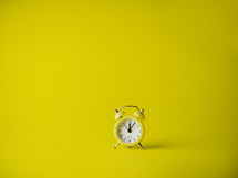 Yellow alarm clock over a yellow background