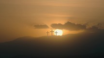 Three Christian crosses silhouette in the mountains at sunset