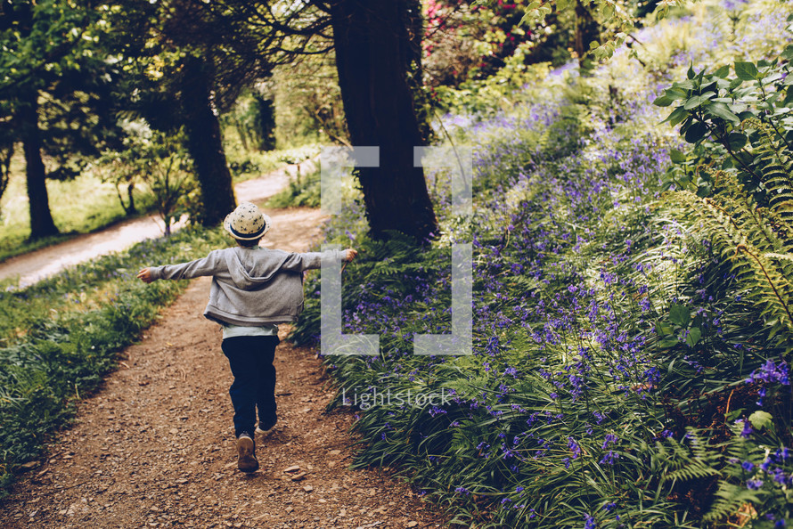 a boy walking on a path in the woods 