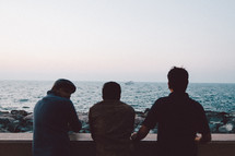 three men looking out at the ocean 