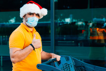 a man wearing a Santa hat and a mask with a shopping cart 