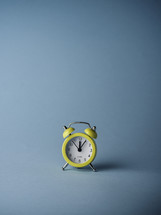 Yellow alarm clock over a turquoise background