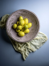 Pink bowl of lemons with fabric on blue background