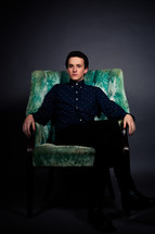 A young man sitting in a green chair 