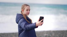 Young girl making a selfie with her smartphone at beach.