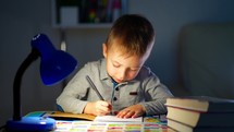 Children and education. Young boy Studying at desk in evening. Pretty little boy writing on a notebook. Young caucasian male child is very concentrated doing his homework at desk in his room.