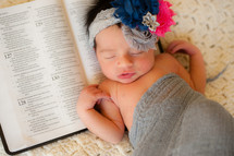 newborn baby sleeping on a Bible 