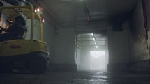 Forklift lifting pallets in a dark cooled warehouse