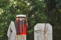 sun tea brewing outside on a fence