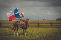 man riding a horse holding a Texas flag