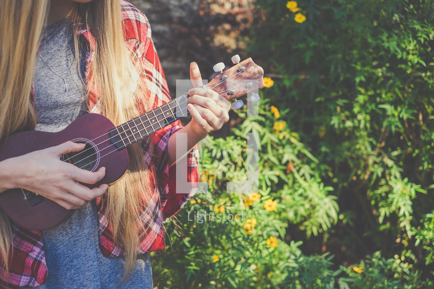 A young woman plays a ukulele.