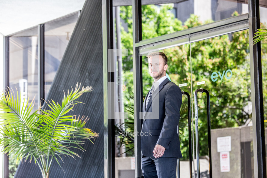 portrait of a businessman standing in front of a glass door 