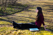 a girl sitting in warm sunlight with a notebook 