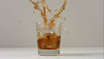 dropping ice into whisky 