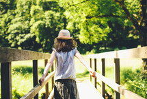 a girl walking across a footbridge 