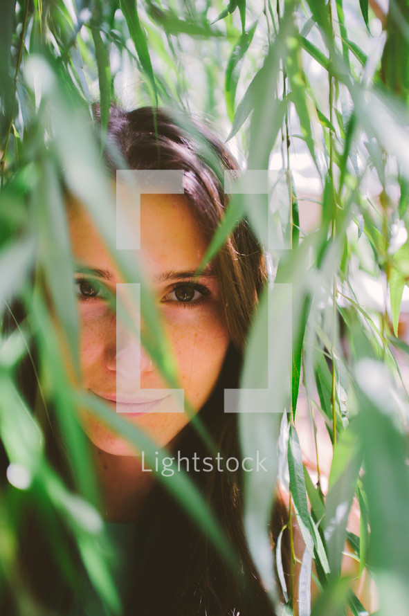 teen girl looking through bamboo leaves 
