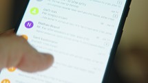Close up of hand browsing through emails on a smartphone screen
