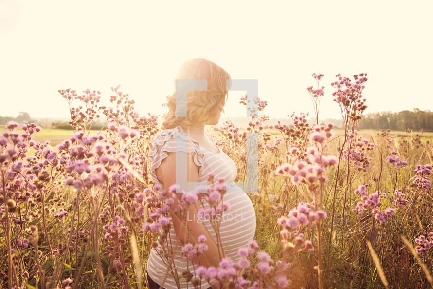 pregnant woman standing in a field of wildflowers