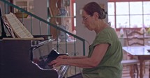 Senior woman playing a large grand piano at her home