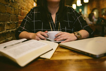 woman reading a Bible and journaling in a coffee shop 