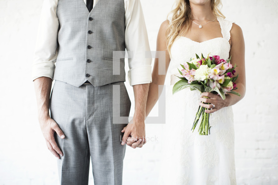 portrait of a bride and groom holding hands together. 