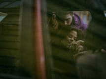 a woman riding in the backseat of a car and man telling her goodbye