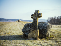old cross and stone in a field 