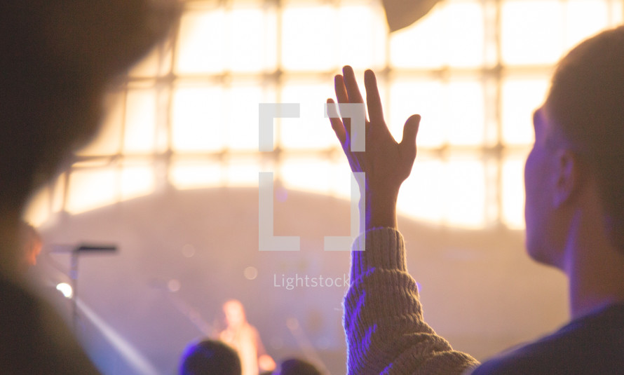 a man with raised hands at a concert 
