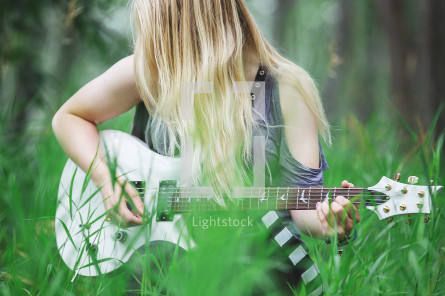 a young woman playing a guitar outdoors 