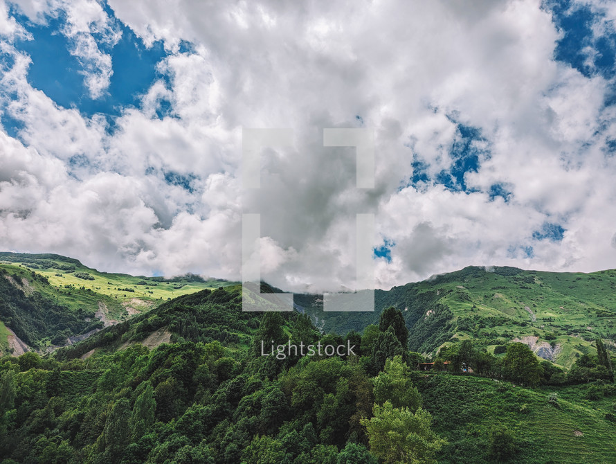 Cloudy blue sky and green mountains