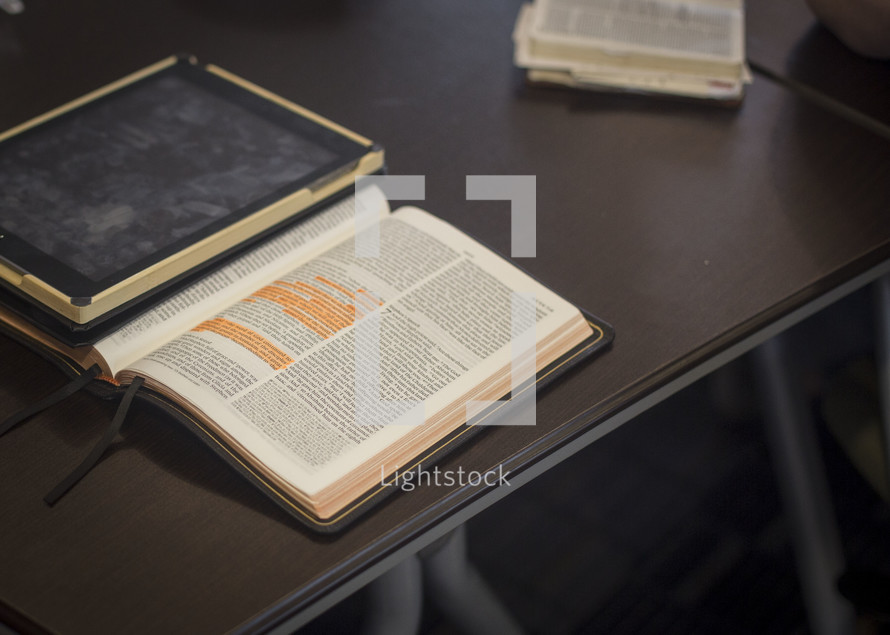 A table with a journal and an open Bible with highlighted verses.