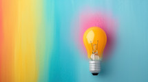 Yellow light bulb on a vibrant rainbow background, symbolizing creativity, innovation, and bright ideas. Perfect for brainstorming and inspirational concepts.