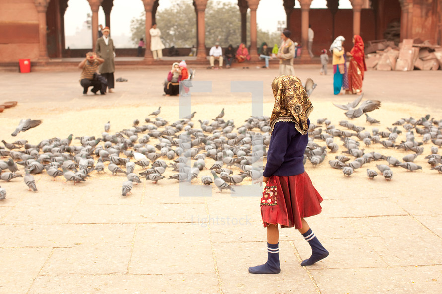 a young girl feeding pigeons in India 