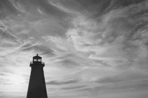 silhouette of a lighthouse under a cloudy sky
