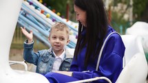 Happy family is smiling and laughing. Parent receives emotions with child in amusement park. Happy childhood. Spending time in outdoor .