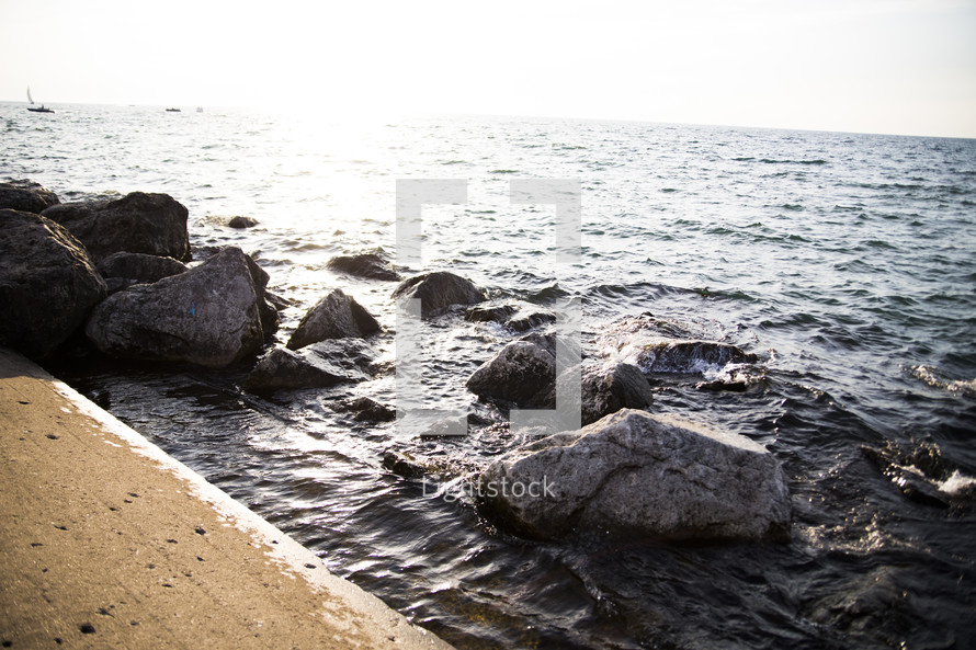 rocks along an ocean shore and concrete wall 