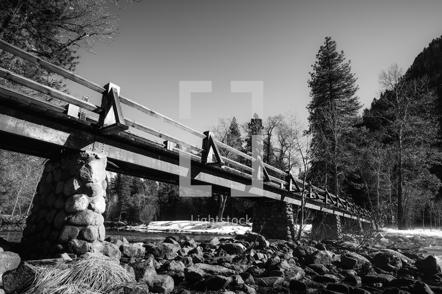 Bridge crossing water with snowy banks - black and white