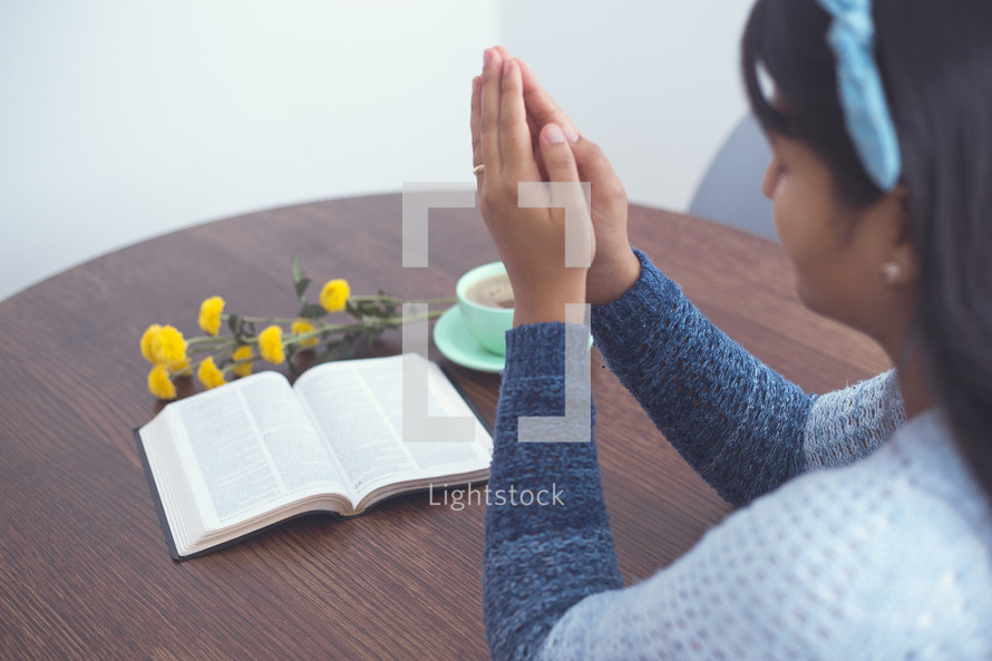 praying hands and Bible on a table 